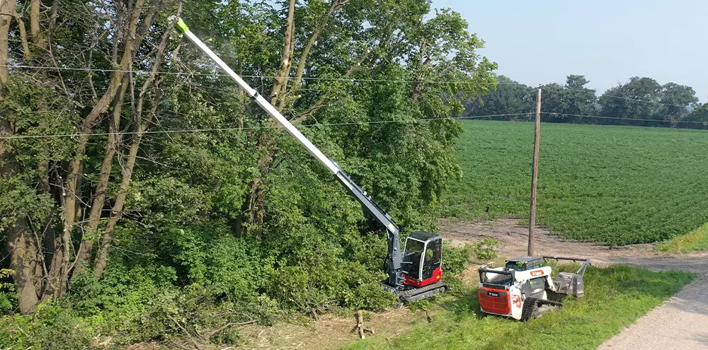 Image showing the Loftness Kwik-Trim and Battle Ax S Series working along a tree line and electric poles.